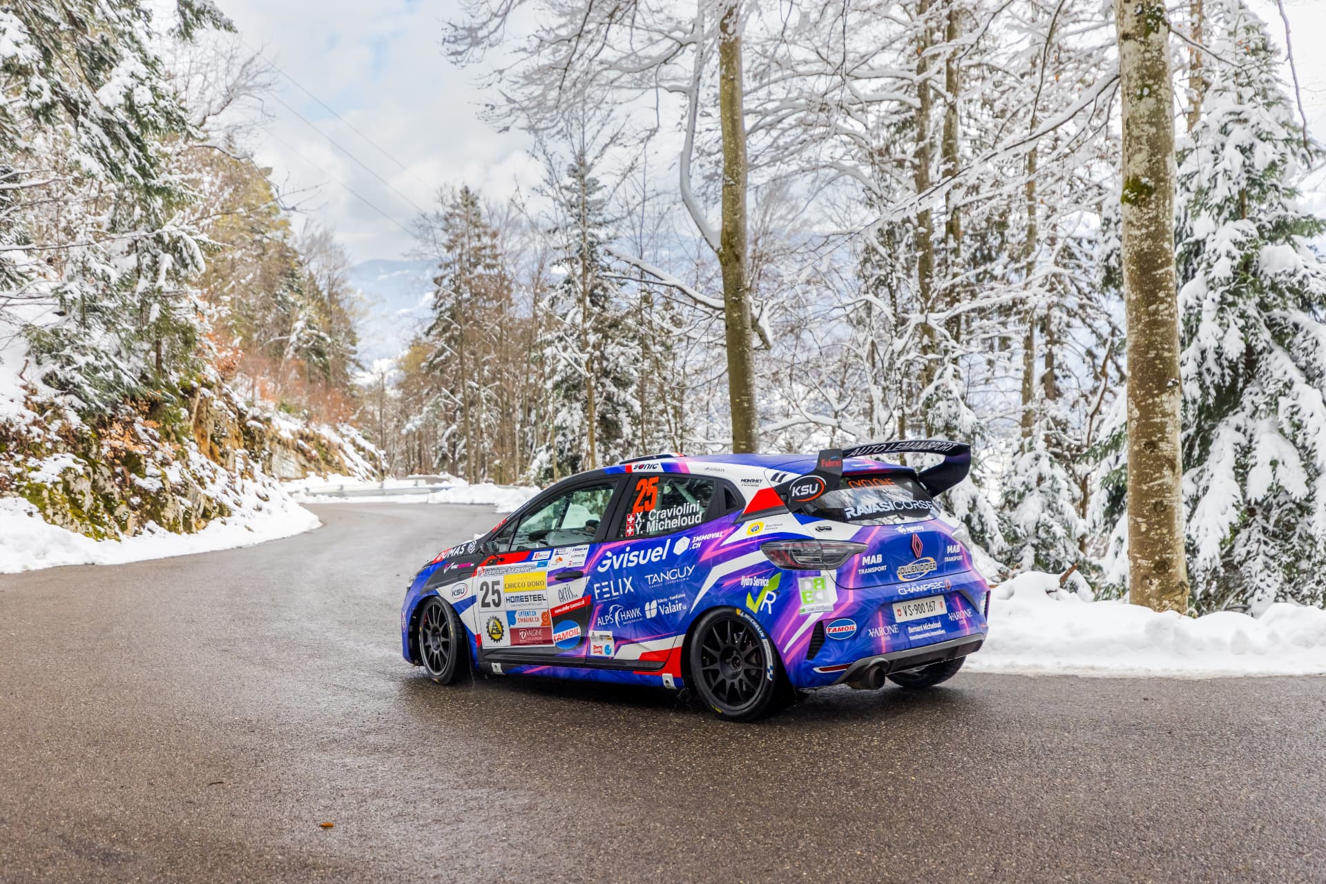 Trois quarts arrière de la Clio Rally3 n°25 dans la forêt enneigée du Jura