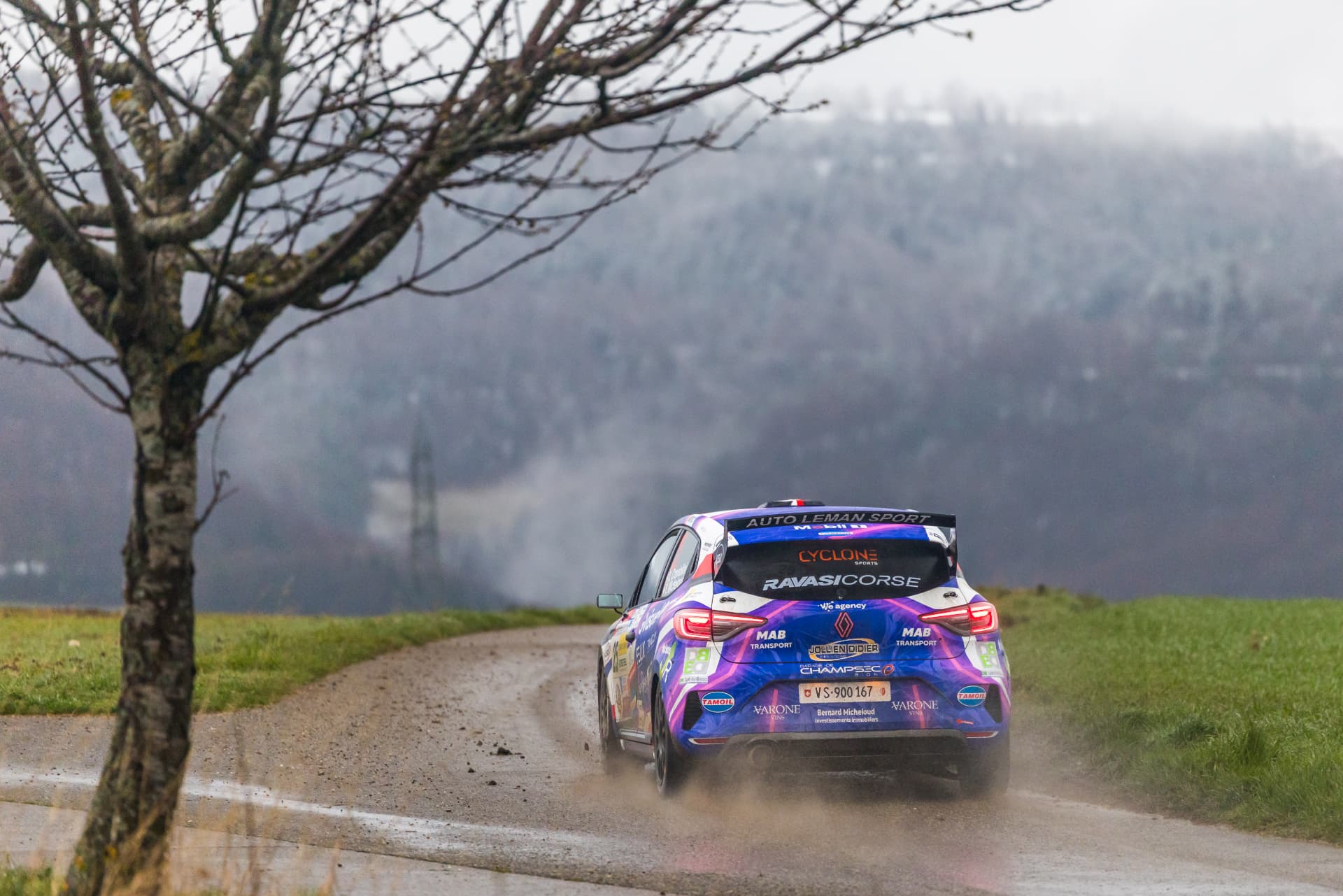 Vue arrière de la Clio Rally3 n°25 en pleine attaque sur route détrempée
