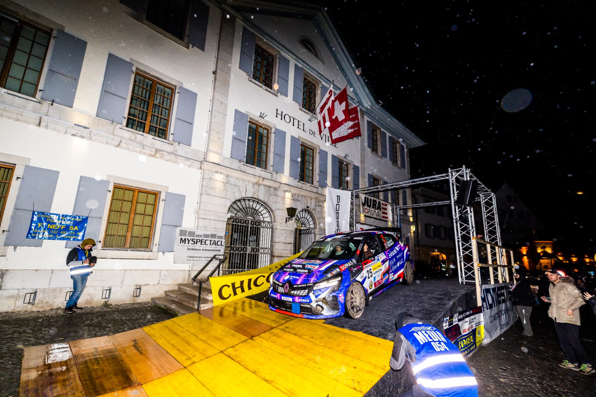 La Clio Rally3 n°25 sur le podium nocturne devant l'Hôtel de Ville, Critérium Jurassien 2026
