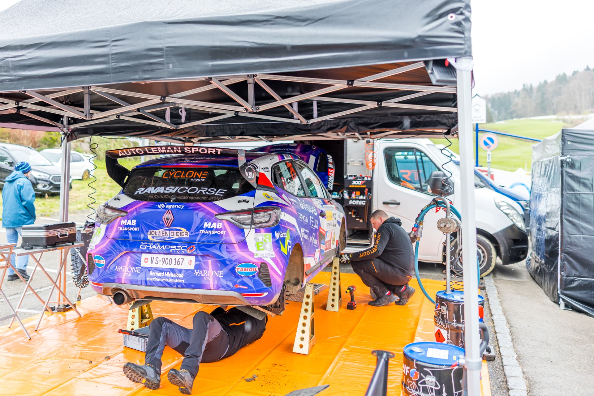L'équipe d'assistance au travail sur la Clio Rally3 n°25 sous la tente