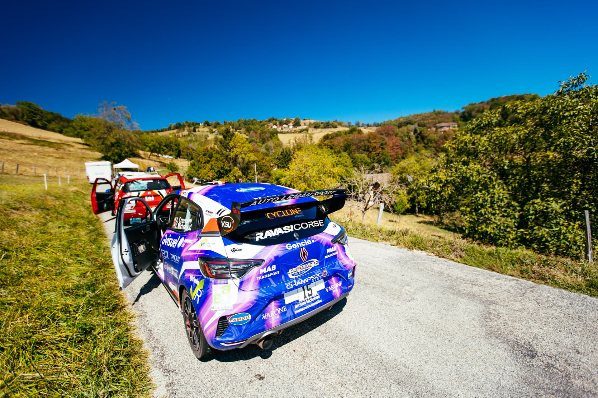 Vue arrière de la Clio Rally3 n°15 en pleine campagne avant une spéciale