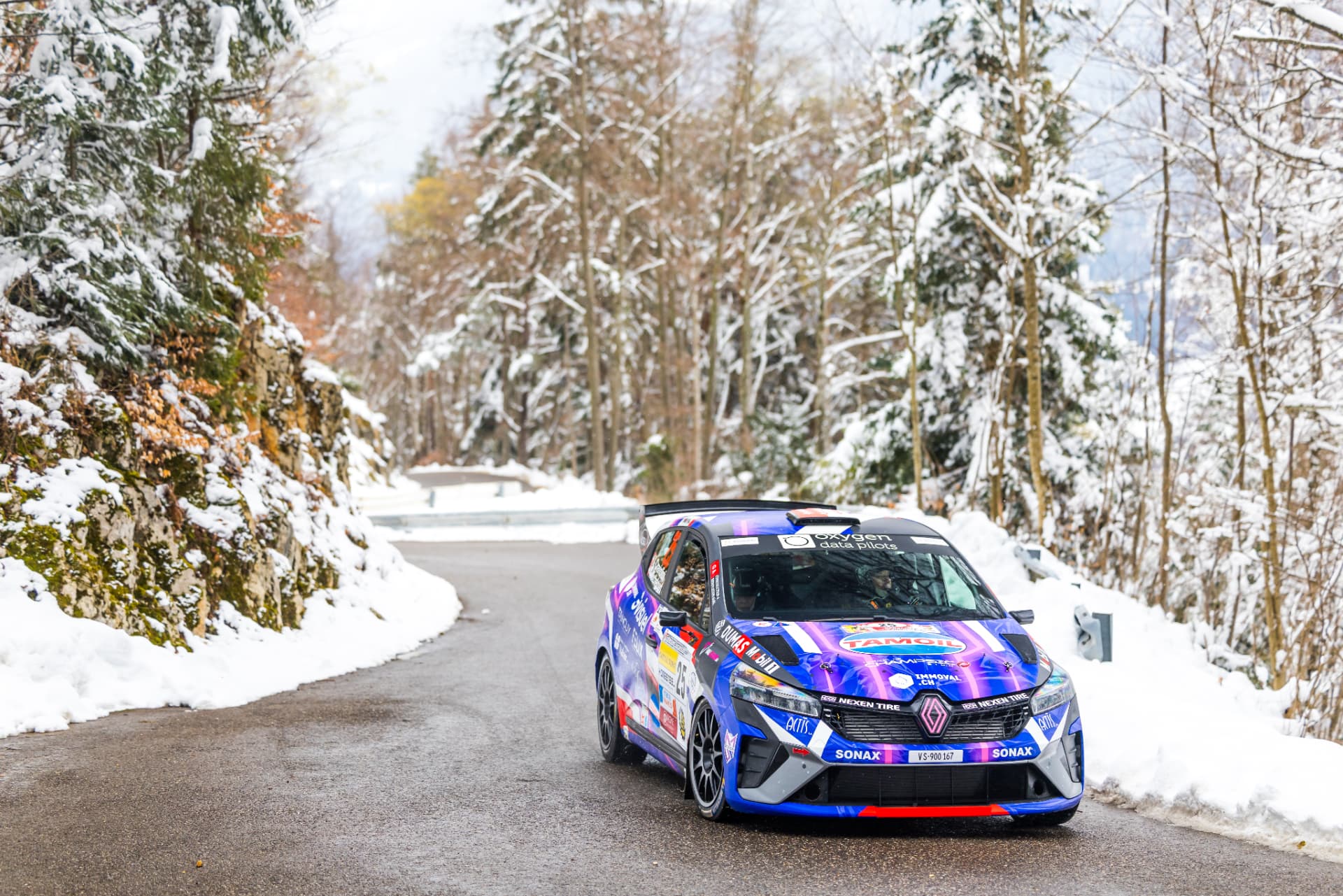 Trois quarts avant de la Clio Rally3 n°25 sur une route bordée de neige